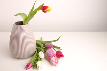 White spring tulips in a vase on a white table. Mock up for displaying works