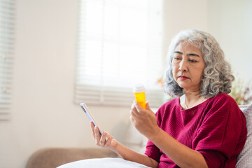 Health care concept, asian senior woman using smart phone reading, searching prescription on bottle medicine, pill label text about information online, instructions side effects, pharmacy medicament.