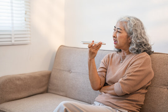 Happy grandmother hold smartphone record audio message talking on gadget at home, smiling modern mature woman using cellphone with virtual digital voice assistant, technology concept