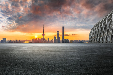 Fototapeta premium Asphalt road with city skyline at sunrise