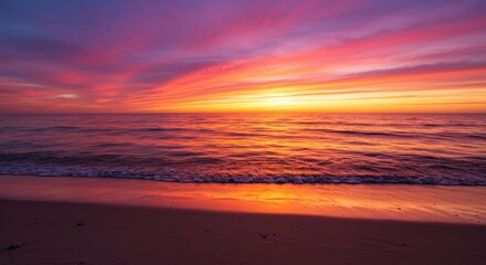 Fototapeta premium Vibrant sunset over calm ocean waves with colorful sky reflecting on sand