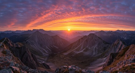 Naklejka premium Majestic sunrise over mountain peaks with vibrant clouds and serene valley below