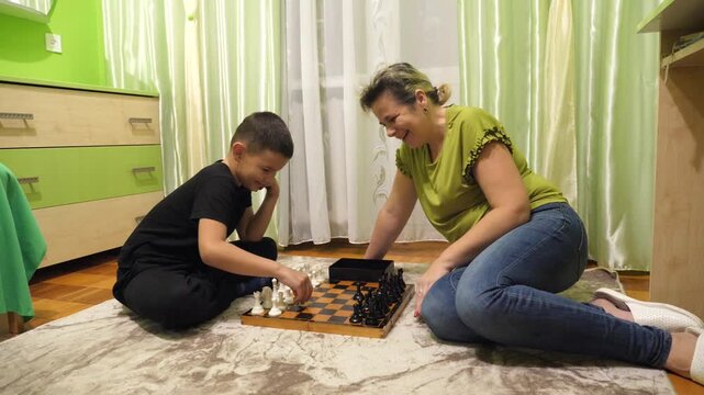 Mother and son playing chess at home. Leisure and board games.