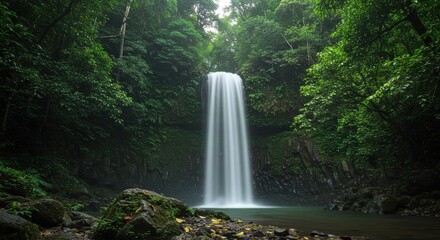 Obraz premium Majestic waterfall cascading into serene pool surrounded by lush greenery