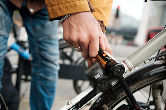 Unrecognizable cyclist locking bike on city street.