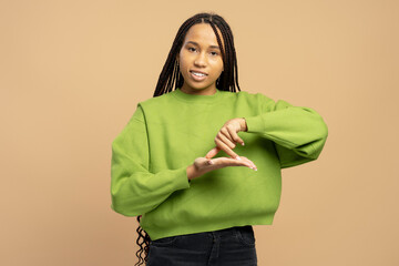 Young woman showing timeout gesture with hands on beige background