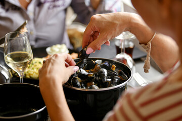 Woman's hands holding mussels over a pan of mussels in a fish restaurant