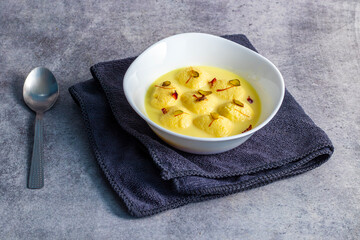 Rasmalai is a soft, spongy Indian dessert made of chhena (paneer) dumplings soaked in sweet, flavored milk, garnished with saffron, cardamom, and nuts.