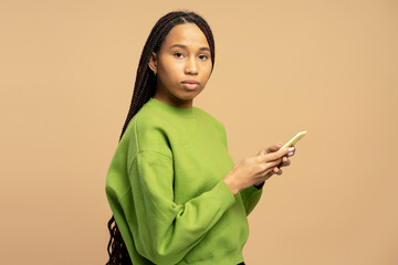 Young woman using smartphone, wearing green sweater and long braids hairstyle