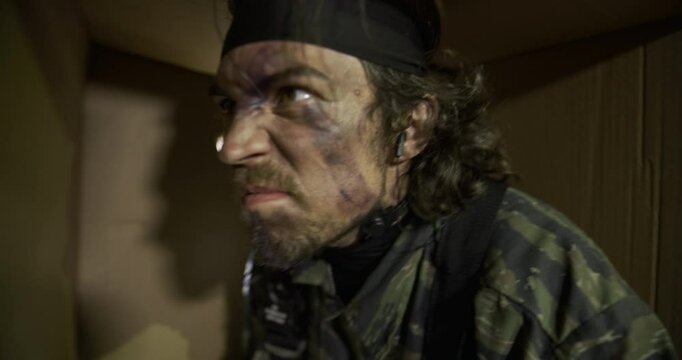 Spy wearing camouflage and war paint shaking comically inside violently moving box - closeup