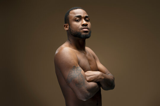 Confident muscular african american man posing with crossed arms and tattoo