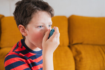 Young boy using inhaler for asthma relief in a cozy living room