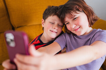 Two children enjoy a playful moment taking selfies together