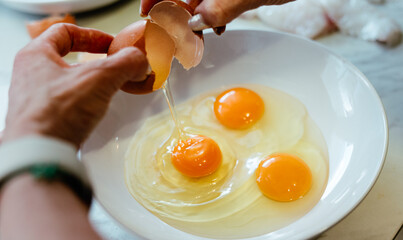 Cracking fresh eggs into a white bowl