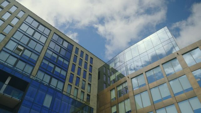 Low Angle View of Modern Glass Buildings with Blue Sky and White Clouds 4K
