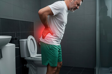 Man Experiencing Lower Back Pain in Bathroom: Health Issue, Treatment, and Care