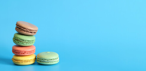 Several colorful macarons close-up. Bright French macarons on blue background, side view. Assortment of macarons with different flavors. Delicious pastries, cookies, food background. Stack of sweets