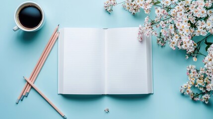 Open big book with clear white pages, with colored pencils, coffee cup, and flowers on a blue background. Flat lay, top view, copy space mockup. Stock photo contest winner.