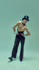 Stylish dancer in fitted corset and striped trousers bending in dynamic pose against muted green...