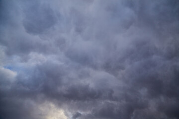 Dense gray clouds in the evening sky, through which the last rays of the setting sun break through. A magical combination of dark shadows and warm highlights of sunlight.