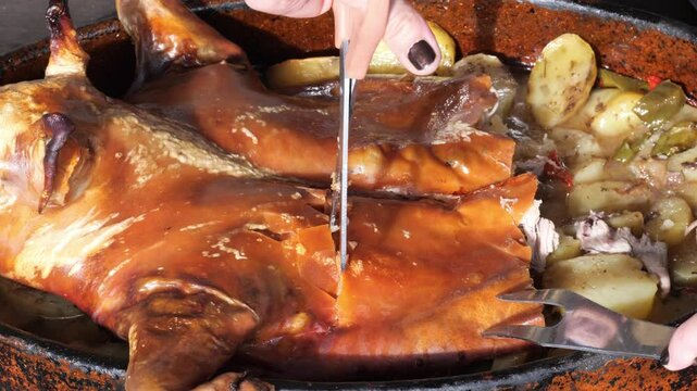 Roast suckling pig with potatoes being carved