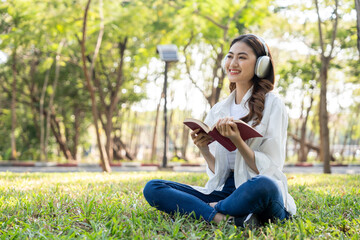 Young asian woman relaxing reading book sitting at public park life style outdoor. Happy female Take a break enjoy time living in the nature. Human and nature together