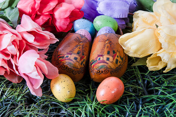 old wooden shoes in green grass with colored Easter eggs and tulips