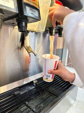 Refreshing beverage being dispensed from a soda fountain into a cup, showcasing the enjoyment of soft drinks and the convenience of self-service beverage stations concept