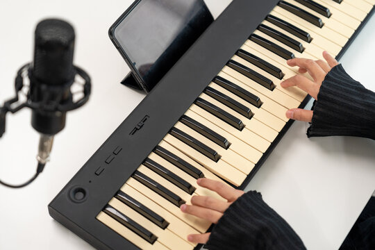 Professional Musician with condenser microphone and tablet for Mixing Mastering music. Music composer woman composing a song with guitar and piano keyboard at digital Recording home studio - Powered by Adobe