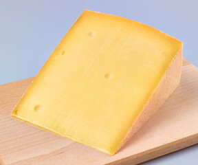 Bergkaese auf hellem Holzbrett, kaesestueck, isoliert, 