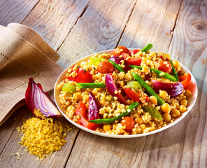 Bulgurpfanne mit roter Zwiebeldeko und heller Serviette auf rustikalem Holzfond, Reisgericht, Gemüse, Tellergericht, 