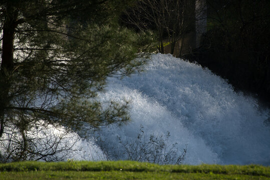 A waterfall flowing from a reservoir in the middle of a forest on a spring evening
