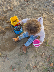 little girl playing in the sand in the autumn park