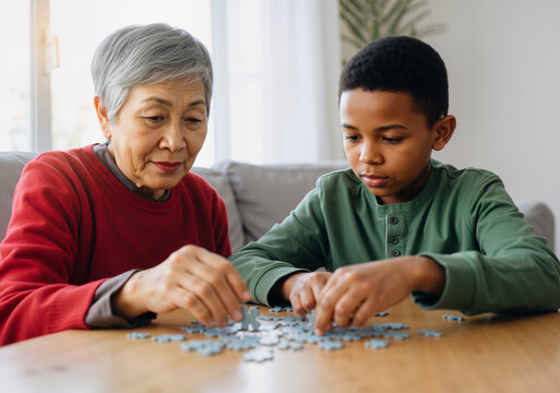 Elderly woman and young boy assembling jigsaw puzzle, enjoying leisure time together