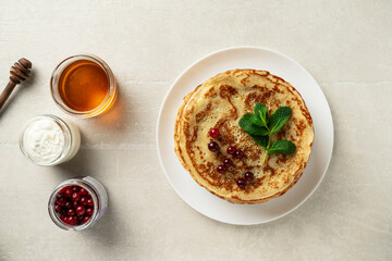 Large pancakes on a light stone background are served by a female cook, top view, home cooking, Maslenitsa, Easter