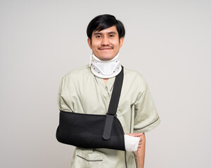 Happy young asian man broken arm on isolated background. Asian man put on plaster bandage cast...