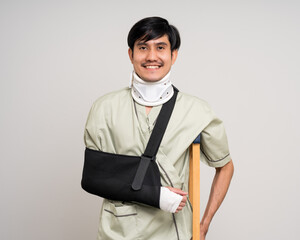 Happy young asian man broken arm on isolated background. Asian man put on plaster bandage cast...