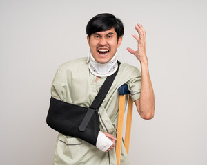 Depressed upset man suffering from pain. Broken arm. Asian man put on plaster bandage cast splint....