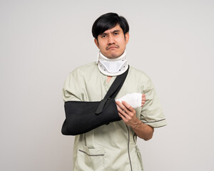 Depressed upset man suffering from pain. Broken arm. Asian man put on plaster bandage cast splint....