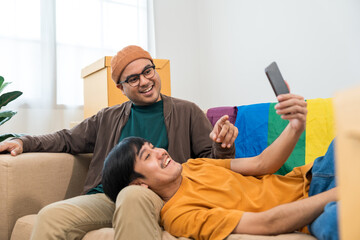 Fototapeta premium The LGBT couple asian family buying new house. Moving relocation with parcel box cardboard. They relax in living room LGBT lifestyle.