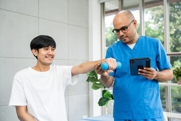 Physical therapy. Male Nurse aids young man in recovering from spine injury and providing...