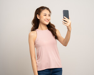 Naklejka premium Pretty young asian woman using cellphone standing on isolated white background. Happy Excited Beautiful young asian shopping online payment with mobile phone. Playing game on smartphone
