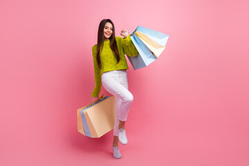 Happy woman holding shopping bags wearing trendy knitwear on pink background, stylish and...
