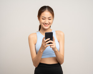 Fototapeta premium Young beautiful asian woman with sportswear using smartphone on isolated white background. Attractive Portrait latin sporty woman standing pose holding cell phone exercise workout in studio.