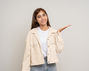 Beautiful smiling happy young asian woman pointing finger. Charming female lady open hands palm up holding something on isolated white background. Asian woman looking blank space.