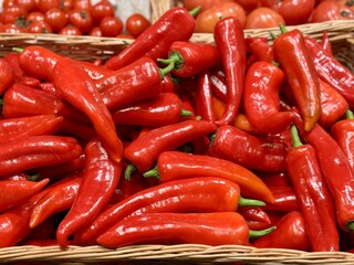 Vibrant red bell peppers are abundant in a market basket, showcasing their freshness and vivid color. Close-up