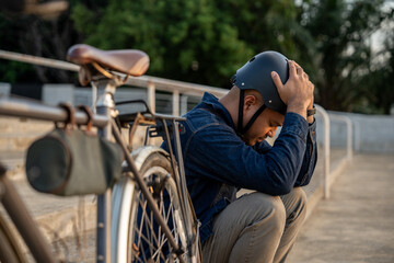 Obraz premium Stressed asian tourist man sitting near bicycle in the urban city background