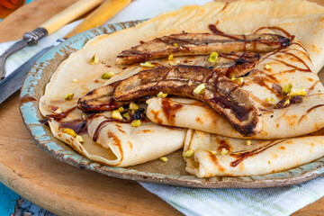 Homemade crepes with caramelised bananas and crushed pistachio nuts