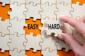 Fototapeta premium Easy or Hard symbol. Concept word Easy or Hard on wooden puzzle. Businessman hand. Beautiful orange background. Business and Easy or Hard concept. Copy space