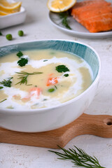 Cream soup with smoked trout, green peas and cream, served in a ceramic bowl. Hot comfort food